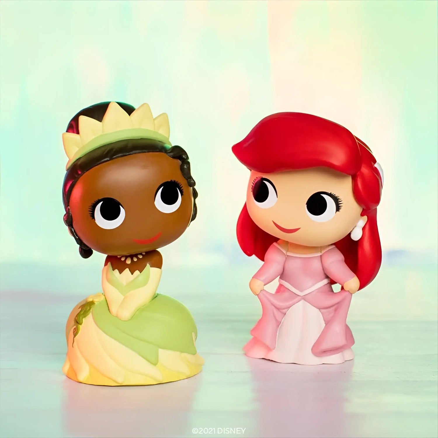 Figurinas de princesas Disney: una en vestido verde y corona, otra pelirroja en rosa.